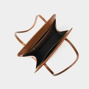 Detail view of the brown leather tote bag interior with labeled functional compartments