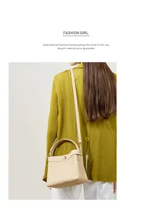 Detail of a beige pebbled leather bucket bag with gold twist lock and shoulder strap