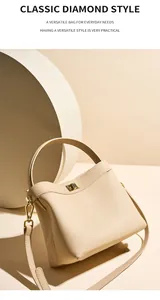 Detailed close-up of beige lychee grain leather handbag with gold metal twist lock