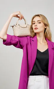 Close-up of cream woven leather handbag with compact top handle and flap detail
