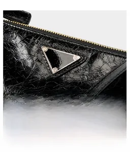Detailed view of black oil wax leather texture with golden zipper and triangle metal logo