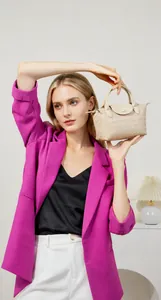 Close-up of beige woven leather dumpling bag with textured top handle on model