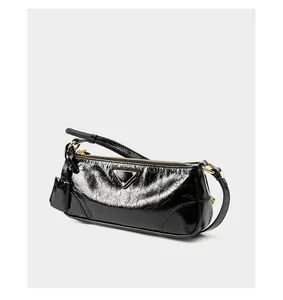 Detailed view of black oil-wax leather texture with golden hardware and small pouch
