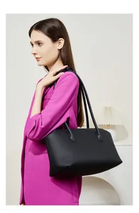 Dettaglio della borsa tote in pelle martellata nera indossata da una modella in rosa