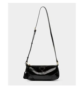 Detail of glossy black wax leather shoulder bag with gold metal zipper and logo
