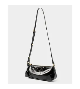 Macro detail of glossy oil wax leather texture and golden metal hardware on black bag