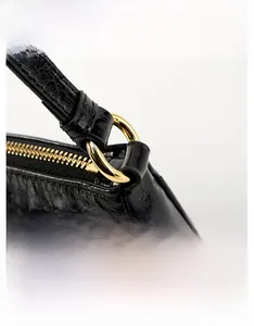 Detail of black oil wax leather shoulder bag with golden metal ring and zipper hardware