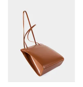 Détail du soufflet latéral et des coutures d'un sac cabas en cuir couleur caramel