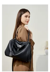 Modella che indossa una grande borsa tote in pelle nera con dettaglio lucchetto chic