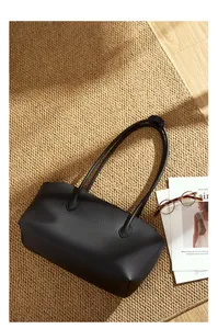 Vista piatta della borsa tote in pelle nera a grana con manici lunghi su un tappeto
