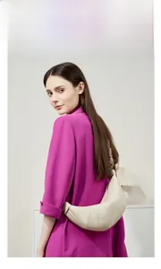 Creamy white leather croissant bag featuring pleated details and crescent shape on a model