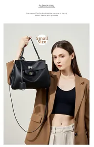 Dettaglio della borsa tote in pelle nera con chiusura a scatto argento su blazer cammello