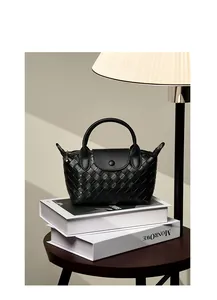 Close-up of black woven leather mini bag with round handles on decorative books