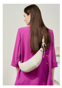 Chic beige leather croissant bag with knotted strap worn over a purple blazer