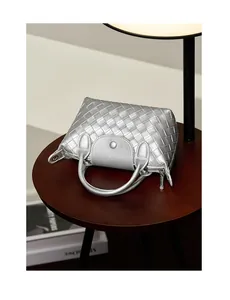 Detailed view of silver woven leather mini bag with metal clasp on wooden table