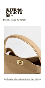 Detail of the flat curved leather handle and gold metal twist lock on a beige bucket bag