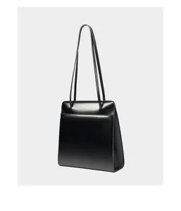 Détail de la texture en cuir noir lisse et des coutures fines sur un sac cabas carré