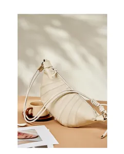 Detail of cream leather croissant bag with quilted pleats and knotted strap design