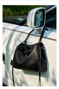Dettaglio della borsa hobo in pelle nera con chiusura argento su uno specchietto
