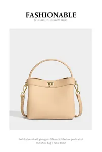 Detail view of beige lychee texture leather bucket bag with gold lock and strap