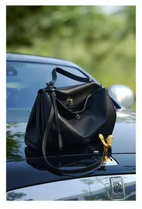Dettaglio di una borsa tote grande in pelle nera con chiusura in metallo su un'auto