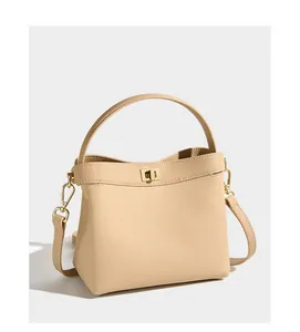 Detail of beige lychee grain leather bucket bag with elegant golden twist lock hardware