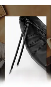 Detail of premium black leather croissant bag showing sleek zipper and drawstring finish