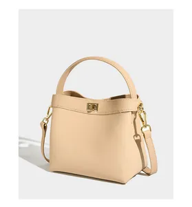 Detailed close-up of apricot leather bucket bag featuring gold twist-lock and fine texture