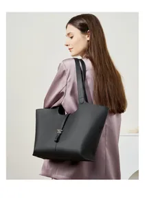 Dettaglio della grande borsa tote in pelle nera a grana indossata da una modella
