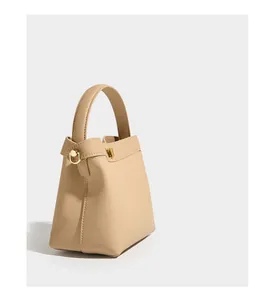 Detail of lychee pattern beige leather bucket bag with golden metal hardware and handle