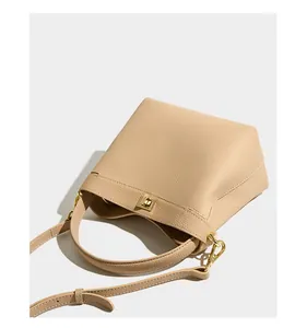 Close-up of beige leather bucket bag with litchi texture and golden metal lock detail