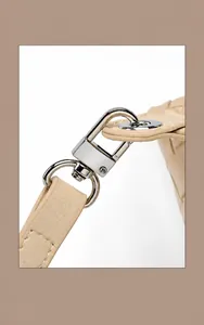 Macro shot of polished metal swivel clasp and woven leather texture on beige bag