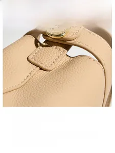 Detail of lychee pattern leather with white stitching and golden metal buckle on beige bag