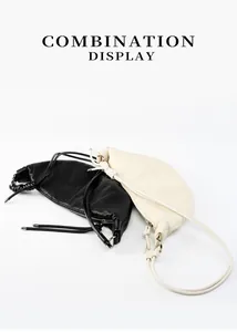 Detailed view of pleated leather croissant bags in black and beige with sleek stitching