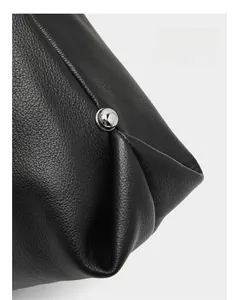 Detail of black lychee grain leather tote showing side folding seam and silver stud
