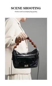 Détail du sac en cuir ciré noir avec poignée en perles ambre et poche à fermoir pivotant
