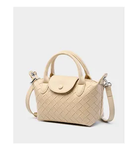Detailed close-up of premium woven leather texture and crossbody strap on off-white handbag