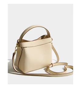 Macro shot of off-white lychee grain leather bucket bag with brown trim and gold hardware