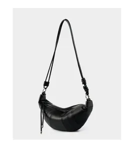 Detailed close-up of a black leather croissant bag with knotted strap and silver zipper