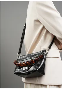Détail d'un sac bandoulière en cuir huilé vintage avec perles d'ambre et fermoir argenté