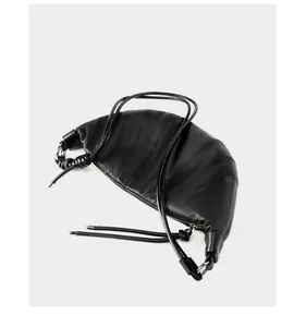 Detail view of black leather croissant bag showing quilted texture and side knot detail