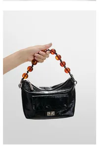 Détail du sac en cuir plissé noir avec poignée en perles d'ambre et fermoir rotatif argenté