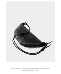 Detail of black sheepskin croissant bag with intricate stitching and soft leather texture