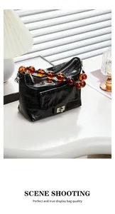Détail du sac en cuir plissé noir avec fermoir argenté et poignée en perles ambre