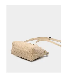 Detailed view of cream woven leather texture and silver buckle on a crossbody bag