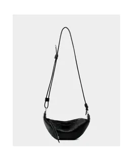 Detail of black leather croissant bag showing segmented stitching and smooth texture
