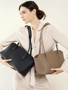 Borse tote minimaliste in pelle martellata nera e taupe indossate da una modella