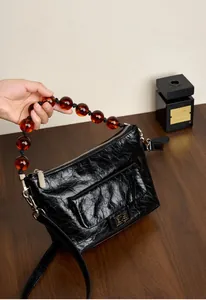 Détail du sac en cuir plissé noir avec poignée en perles d'ambre et garnitures argentées
