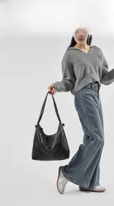 Detail view of a black leather tote bag featuring smooth natural texture and wide strap