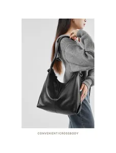Close-up of black leather hobo bag with lychee texture and metal zipper on model